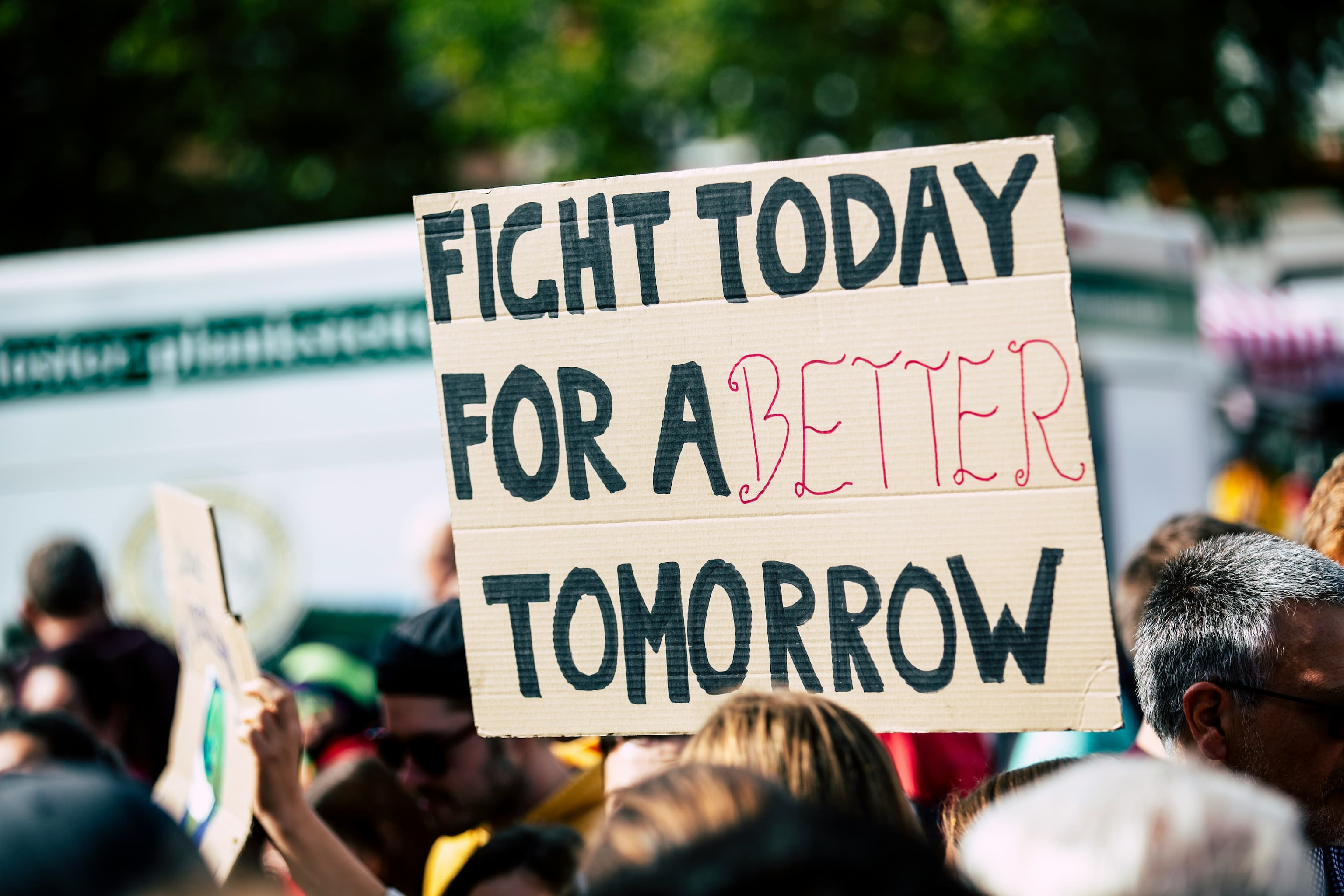Image of a person holding a sign that says 'Fight Today for a better Tomorrow'.